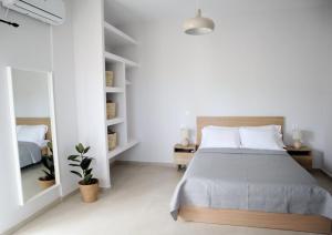 Habitación blanca con cama y espejo en Villa Elea Apartments, en Spiliá