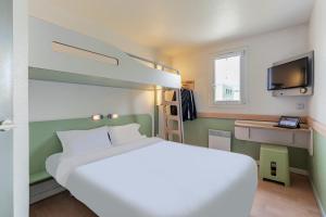 Cette chambre comprend un lit et une télévision. dans l'établissement B&B HOTEL Strasbourg Nord Schiltigheim, à Schiltigheim