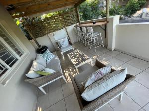 an outdoor patio with a couch and chairs and a bar at PIGEONWOOD Forest Cottage in Ballito