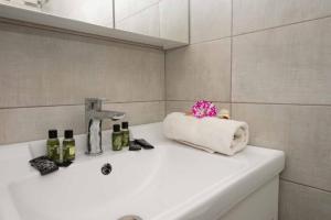 un lavabo de salle de bain avec un porte-serviettes et un robinet dans l'établissement Lollas Apartments Acharavi Corfu, à Acharavi