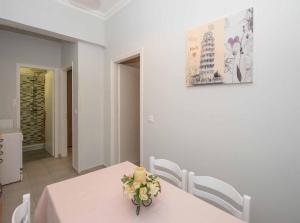une table de salle à manger avec un vase de fleurs dessus dans l'établissement Lollas Apartments Acharavi Corfu, à Acharavi