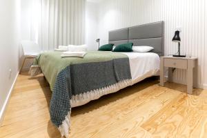 een slaapkamer met een groot bed met groene kussens bij Delmar I in Nazaré