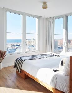 a white bedroom with a large bed and large windows at The Rockaway Hotel in Queens