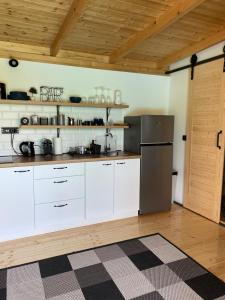 eine Küche mit weißen Schränken und einem Kühlschrank aus Edelstahl in der Unterkunft Woody House in Krčedin