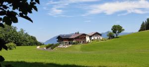 een huis op een heuvel met een groen veld bij Gästehaus Lärcheck Berchtesgaden FeWo Wiesentraum in Berchtesgaden