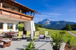 a patio with chairs and a table with mountains in the background at Gästehaus Lärcheck Berchtesgaden FeWo Bergfeuer in Berchtesgaden