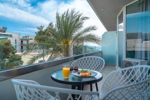 un tavolo con un bicchiere di succo d'arancia sul balcone di Maison 66, Riviera Hotels ad Atene