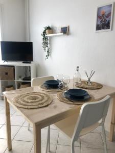 una mesa de comedor con platos y vasos. en Jeter l’ancre - studio, en Calais