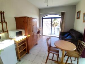 a kitchen and living room with a table and a microwave at Seafront akwador in Il-Ħamrija