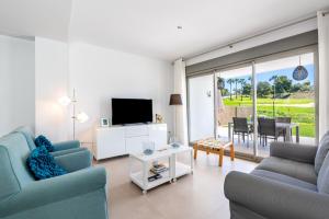 a living room with two blue chairs and a television at Baviera Golf Townhouse in Caleta De Velez
