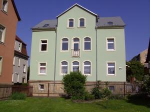 una gran casa verde y blanca con una valla en Ferienwohnung Zirkelstein, en Bad Schandau