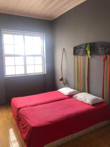 - une chambre avec un grand lit rouge et une couverture rouge dans l'établissement Americo Hostel, à São Luís
