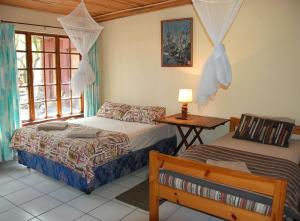 a bedroom with two beds and a table and a window at Kosi Moon Bed and Breakfast in Manguzi