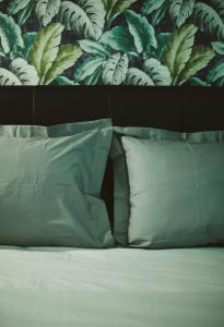 łóżko z 2 poduszkami i ścianą z liśćmi w obiekcie A hidden gem in Volos *LUXURY HOME* w mieście Wolos