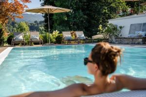 a woman in sunglasses sitting in a swimming pool at Boutique Hotel Relais Chalet Wilhelmy in Bad Wiessee