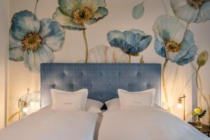 ein Schlafzimmer mit einem Bett mit blauen Blumen an der Wand in der Unterkunft Boutique Hotel Relais Chalet Wilhelmy in Bad Wiessee