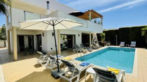 a pool with chairs and an umbrella next to a house at Praia by Check-in Portugal in Albufeira