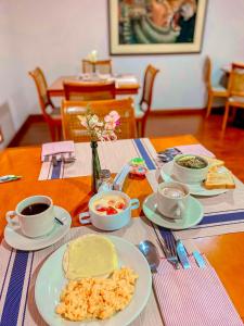 einen Tisch mit Teller mit Speisen und Tassen Kaffee in der Unterkunft Hotel Maceo Chico in Bogotá