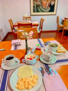 a table with plates of food and cups of coffee at Hotel Maceo Chico in Bogotá