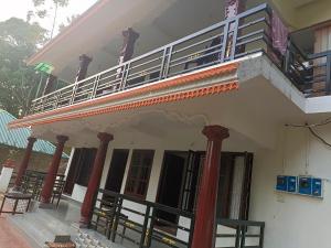 a white building with a balcony and columns at Voyage Munnar Laya Home Stay in Suryanelli