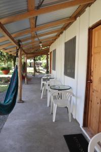 um pátio com mesas, cadeiras e uma rede de descanso em Amaya's Hostel em Jaloba