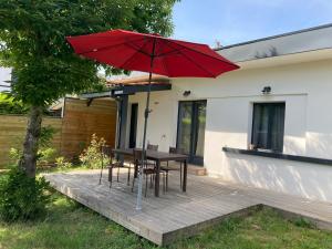 a wooden deck with a table and a red umbrella at Maison de charme in Pessac
