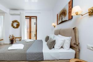 a white bedroom with a bed and a chair at Deluxe Suites in Chania