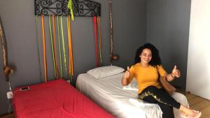uma mulher sentada em uma cama dando os polegares para cima em Americo Hostel em São Luís