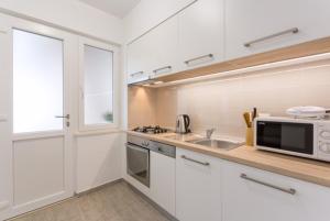 een witte keuken met een wastafel en een magnetron bij Apartment R&R in Dubrovnik