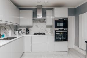 a white kitchen with white cabinets and appliances at The Mulberry in Henley on Thames