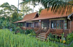 a small house with a deck in a garden at Hanaya Ubud Villa in Ubud
