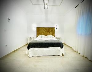 um quarto com uma cama grande num quarto branco em Apartamentos Guaditania em Mérida