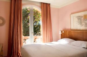 a bedroom with a bed and a large window at Hôtel Le Porquerollais in Porquerolles