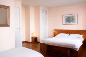 a bedroom with a bed with white sheets and a table at Hôtel Le Porquerollais in Porquerolles