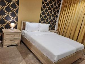 ein Schlafzimmer mit einem großen Bett mit einem Nachttisch und einem Bett der Marke sidx sidx sidx. in der Unterkunft Golden Dahlia Fintas in Kuwait