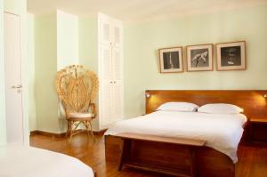 a bedroom with a bed with white sheets and a chair at Hôtel Le Porquerollais in Porquerolles