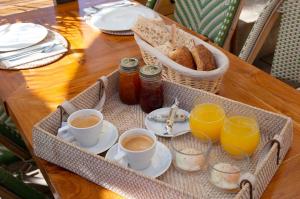 a tray with cups of coffee and bread on a table at Hôtel Le Porquerollais in Porquerolles