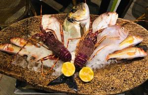 a bunch of fish on a plate with lemon slices at Hôtel Le Porquerollais in Porquerolles