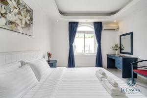 a bedroom with a large white bed with blue curtains at La Casona Hotel in Ho Chi Minh City