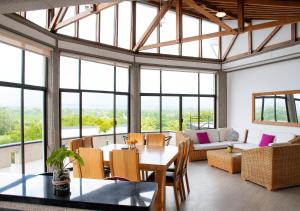 a living room with a table and chairs and windows at Panorama Pueblo Tapao by DOT Boutique in Armenia