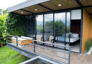 a glass house with a deck with a bed and chairs at Panorama Pueblo Tapao by DOT Boutique in Armenia