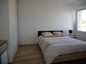 um quarto branco com uma cama e uma janela em Appartement lumineux au calme em La Roche-sur-Yon