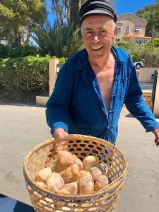 an older man holding a basket of bread at Hôtel Le Porquerollais in Porquerolles