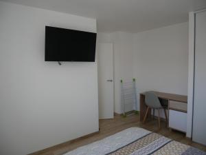 um quarto com uma televisão numa parede branca em Appartement lumineux au calme em La Roche-sur-Yon