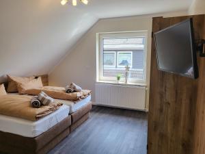 a bedroom with two beds and a flat screen tv at FeWo-Brak in Norden