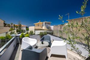 a balcony with white chairs and a table at VaSan suite in Rethymno