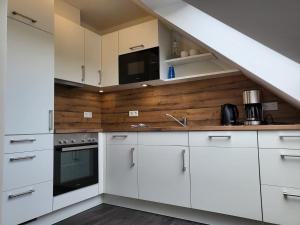 a kitchen with white cabinets and a staircase at FeWo-Brak in Norden