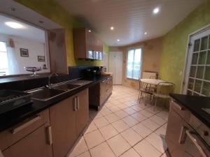 a large kitchen with a sink and a table at aux hirondelles du lac in Le Mêle-sur-Sarthe