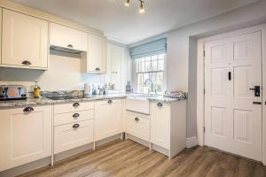 a large kitchen with white cabinets and a window at The Aubrey - a gorgeous converted 17th Century Grade II listed bolthole in Bakewell in Bakewell