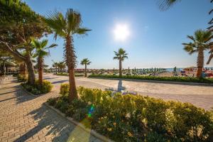 une rue pavée avec des palmiers et la plage dans l'établissement Merar Hotel, à Golem
